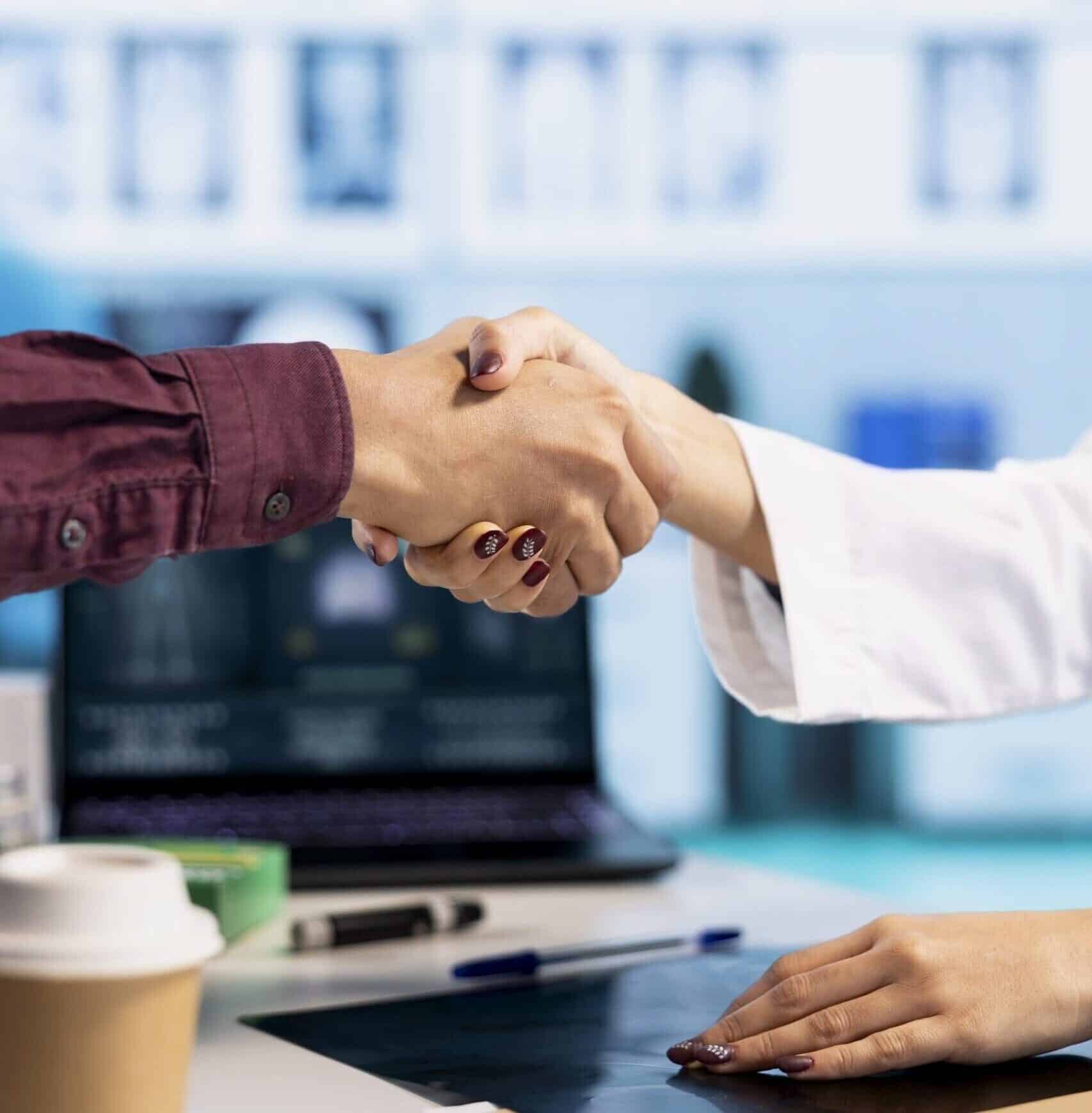 Business handshake between two professionals in an office setting.