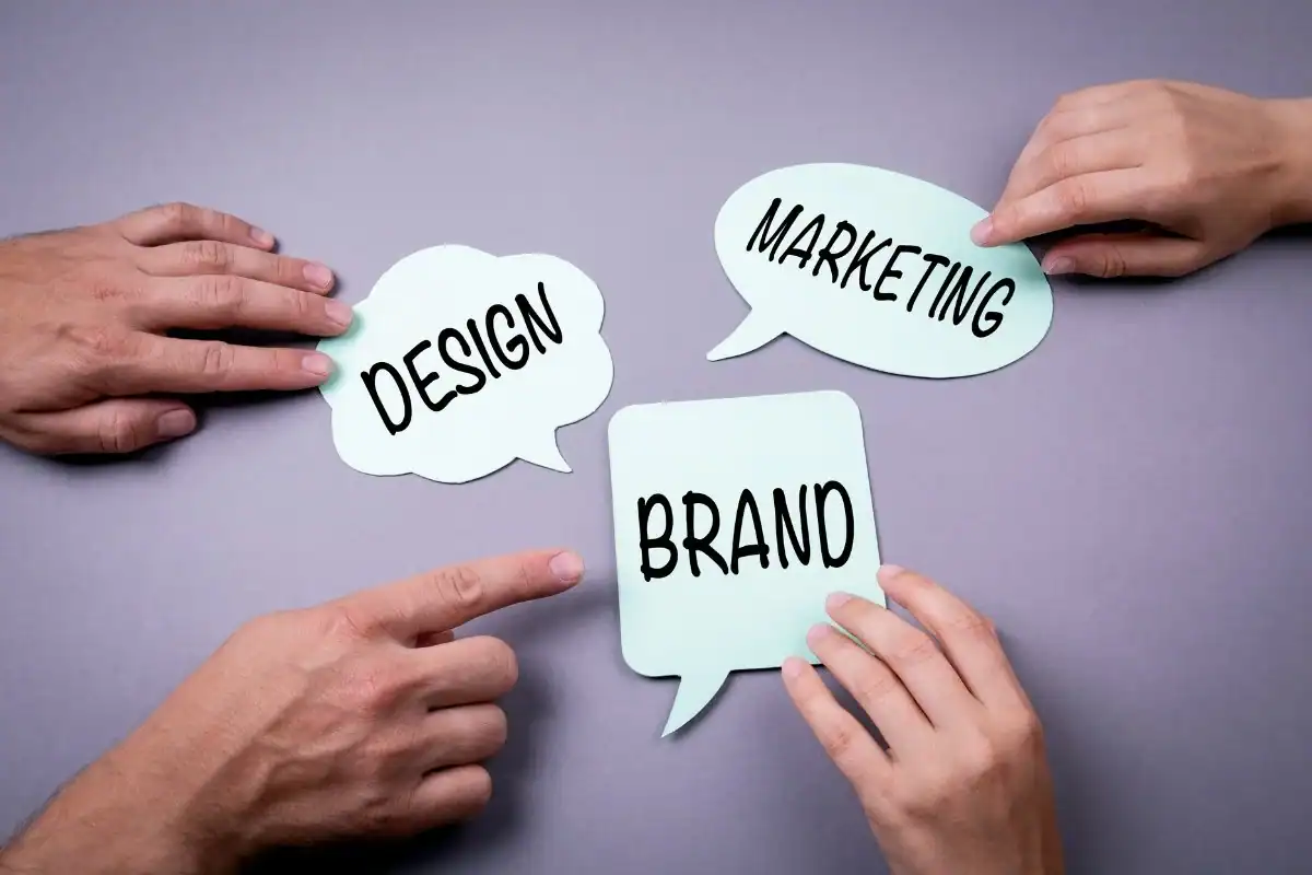 Hands holding paper speech bubbles with "Design," "Marketing," and "Brand" for branding concepts.
